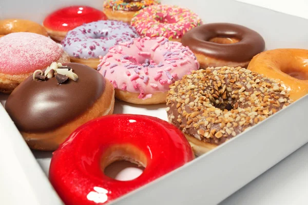 Donuts surtidos con diferentes rellenos en caja de cartón para la entrega de pasteles aislados sobre fondo blanco. Concepto de comida rápida dulce. La torta sabrosa de postre de las rosquillas de la panadería del desayuno — Foto de Stock