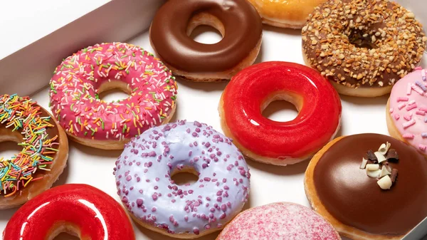 Donuts surtidos con diferentes rellenos vista superior en caja de cartón para la entrega de pasteles aislados sobre fondo blanco. Concepto de comida rápida dulce. La torta sabrosa de postre de las rosquillas de la panadería del desayuno — Foto de Stock