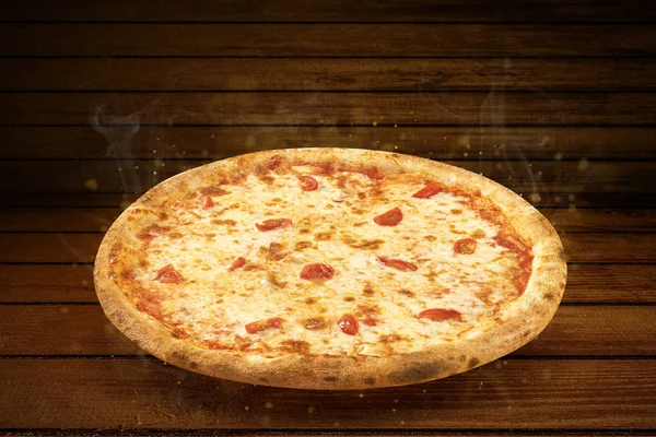 Pizza na mesa de madeira. Flying hot pizza margarita closeup com queijo mussarela, tomate e fumaça de vapor — Fotografia de Stock