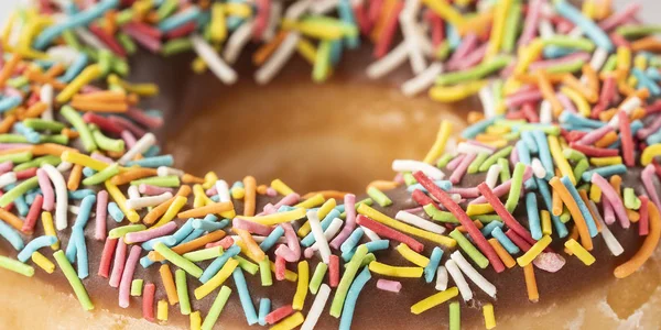 Macro de donut de chocolate colorido. Donut de textura con trozos de nueces primer plano. Banner de comida dulce — Foto de Stock