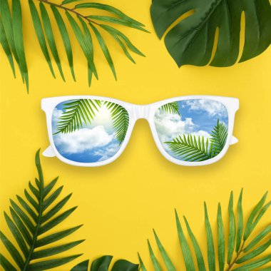 Yaz yaratıcı düzeni güneş gözlüğü yapılmış, sarı arka plan üzerinde tropikal palmiye yaprakları. Kopya alanı ile minimal yaz egzotik kavramı