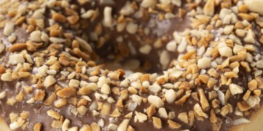 Çikolatalı çörek makro. Fındık parçaları closeup ile Doku donut. Banner tatlı gıda