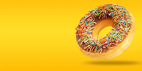 Minimal sweet food concept made of chocolate donut. Colorful donut in flying with copy space on yellow and orange background