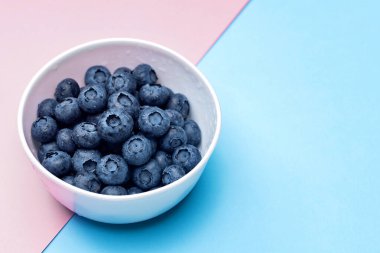 Mavi arka planda su damlaları olan yaban mersini kasesinde. Boşluğu kopyala.