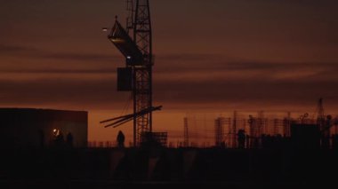 Vinç ve inşaatçılar turuncu gökyüzü arka plan üzerinde bir gökdelen inşa ediyoruz