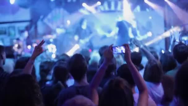 Κορίτσι συλλαμβάνοντας μια συναυλία με ένα smartphone, η μεγάλη ομάδα των ευτυχισμένων ανθρώπων απολαμβάνουν ροκ συναυλία, παλαμάκια με υπερυψωμένο επάνω τα χέρια, τα φώτα από το στάδιο 4 — Αρχείο Βίντεο