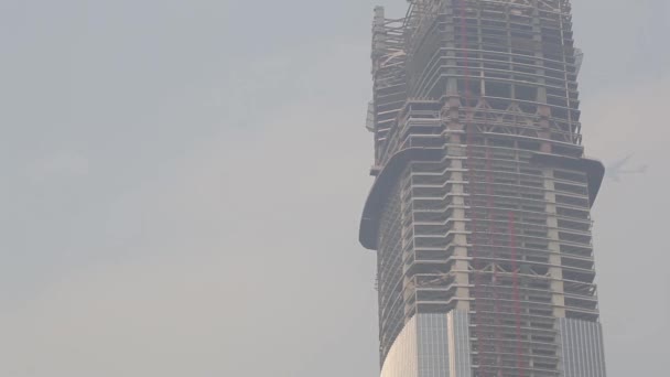 El avión vuela detrás de un rascacielos en construcción — Vídeos de Stock