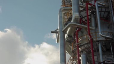 Gökyüzünün arka planında bir petrol rafinerisinin bacası ve boru hatları
