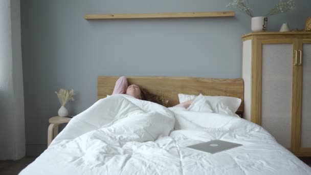 Mujer joven usando portátil en la cama — Vídeo de stock