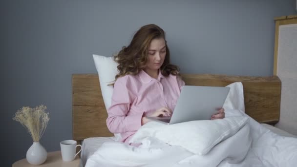 Mujer con portátil en la cama por la mañana — Vídeo de stock