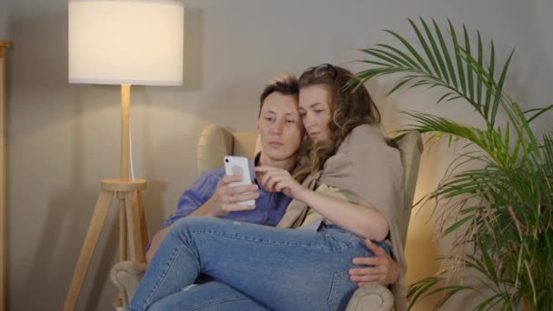 Una pareja cariñosa abrazándose en un sillón. Freelancers felices con laptop — Vídeos de Stock