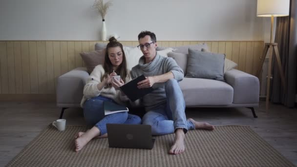 Casal inspirado discutindo planos de projeto. Jovens freelancers com gadget e notepads. — Vídeo de Stock