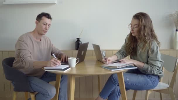 Pareja moderna trabajando con ordenadores portátiles. Pareja joven inteligente discutiendo proyecto en el escritorio — Vídeo de stock