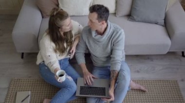 Genç çift oturma odasında dizüstü bilgisayar kullanarak dinleniyor. Dizüstü bilgisayarlı çağdaş çift oturma odasında dinleniyor..