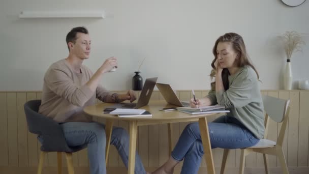 Moderna par arbetar med bärbara datorer. Smart ung par diskuterar projekt vid skrivbordet — Stockvideo