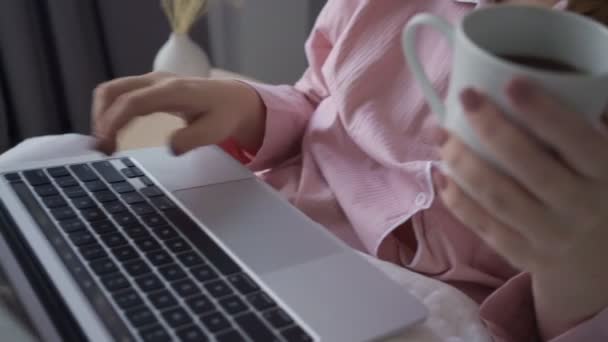 Lächelnde Freiberuflerin mit Laptop und Notizblock im Bett — Stockvideo