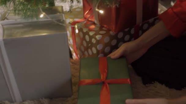 Unerkannte Frau mit Geschenk vor Weihnachtsbaum — Stockvideo