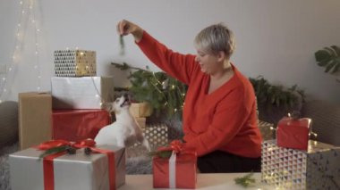 Kadınlar, hayvanlar ve kış tatili konsepti. Hediye kutusunu hazırlayın, yavru köpekle birlikte poz verin. Noel kutlaması. 