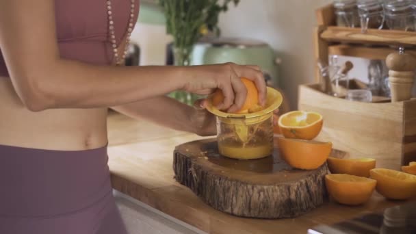 Fitness mujer joven hacer y beber jugo de naranja en la cocina — Vídeos de Stock