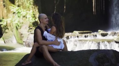 Çift havuzun keyfini çıkarıyor ve büyük şelalenin dibinde dinleniyor. 