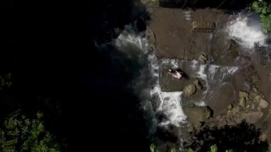 Çift havuzun keyfini çıkarıyor ve büyük şelalenin dibinde dinleniyor. 