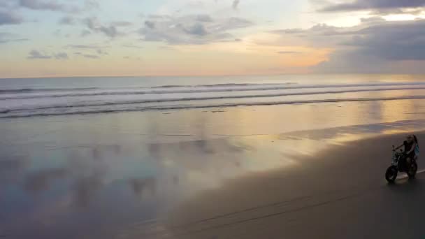 Leidenschaftliches Paar fährt bei Sonnenuntergang auf Motorrad am Strand — Stockvideo