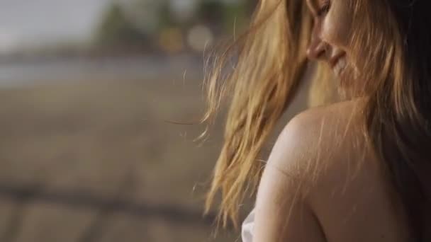 Jonge vrouw in witte jurk lopen alleen op het strand in de zonsondergang — Stockvideo