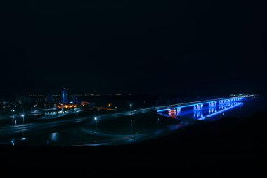 Barnaul şehir Ob nehri üzerinde Gece neon otomotiv köprü, Rusya. Yeni Barnaul köprüsünün mavi aydınlatması. Gece leyin siyan lüminesanı. 17 Nisan 2018'de yüksekten çekilmiş. Upland Park'tan görünüm.