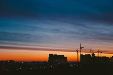 Harika varirenkli canlı şafak ile Cityscape. Şehir binalarının karanlık siluetleri üzerinde inanılmaz dramatik çok renkli bulutlu gökyüzü. Bulutlu havalarda gün doğumunun atmosferik arka planı. Kopyalama alanı.