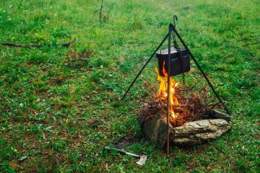 Şenlik ateşinin üstündeki tripodda kazan. Doğada yemek pişirmek. Dışarıda akşam yemeği. Yakacak odun, dallar ve ateşte fırça odun. Aktif istirahat. Kamp. Atmosferik yangın.
