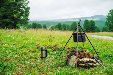 Şenlik ateşinin üstündeki tripodda kazan. Doğada yemek pişirmek. Dışarıda akşam yemeği. Yakacak odun, dallar ve ateşte fırça odun. Aktif istirahat. Dağlarda kamp.