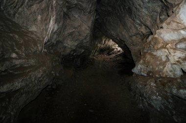 Güzel bir mağara. Karanlık zindandan manzara. Mağaranın dokulu duvarları. Yeraltının arka plan görüntüsü. Mağaranın içinde nem var. Tünelin sonundaki ışık.