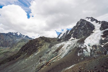 Bulutlu gökyüzü altında karlı dev dağ aralığı. Kar lı kayalık sırt. Büyük bir buzul. Su akıntıları ile buzlu dağ. Harika dağlar. Doğanın atmosferik minimalist dağlık manzara.