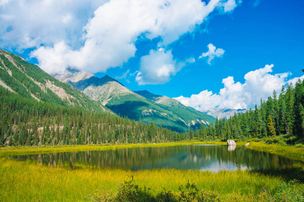 Красивое горное озеро перед гигантскими горами под голубым небом с белыми облаками. Край леса на склоне. Удивительная вода в солнечный день. Прекрасный горный пейзаж. Красочный живописный пейзаж. Горный пейзаж
.