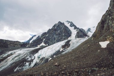 Dağ lık dağda kar. Bulutlu gökyüzü altında atmosferik karlı sırt. Bulutlu havalarda alışılmadık dev kayalar. Dağlarda yükseke tırmanın. Yaylaların görkemli doğasının inanılmaz minimalist manzarası.