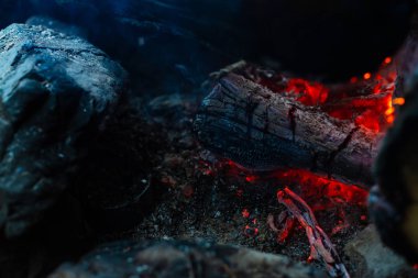 Yanan kütükler canlı ateşte yandı. Kamp ateşi turuncu alev ile atmosferik arka plan. Kopya alanı ile içeriden şenlik ateşi hayal edilemez ayrıntılı görüntü. Duman ve küller yakın.