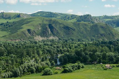 Dağlar ve tepeler arasında inşa edilmiş kulübeler. Altay köyü, Rusya. Manzara.