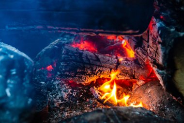 Yanan kütükler canlı ateşte yandı. Kamp ateşi turuncu alev ile atmosferik arka plan. Kopya alanı ile içeriden şenlik ateşi hayal edilemez ayrıntılı görüntü. Duman ve küller yakın.