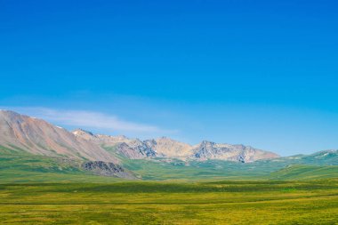 Berrak mavi gökyüzü altında yeşil vadi üzerinde kar ile dev dağlar. Güneş ışığında yaylaların zengin bitki örtüsü ile Çayır. Görkemli doğanın inanılmaz güneşli dağ manzara.