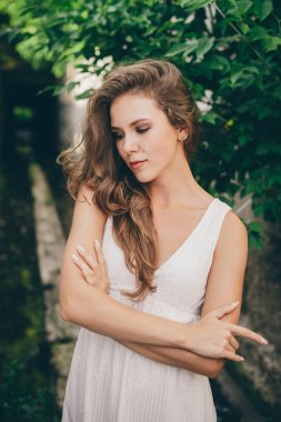Yeşil ağaç yaprakları yakınında beyaz elbise kıvırcık doğal saçlı güzel mutlu kız. Yaz güzellik portresi. Hayalperest bayan doğanın tadını çıkarın. Ormanda uzun tünelde rüya gibi görme ile ilham kadın.