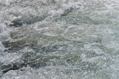 Köpüklü su yüzeyinin doğal dokusu. Nehrin akıntıları yakın çekim. Dağ deresi hızlı akışı. Kopya alanı ile temiz su dalgalarının arka plan. Parlak dere dokulu köpük. Hızlı nehir dokusu.