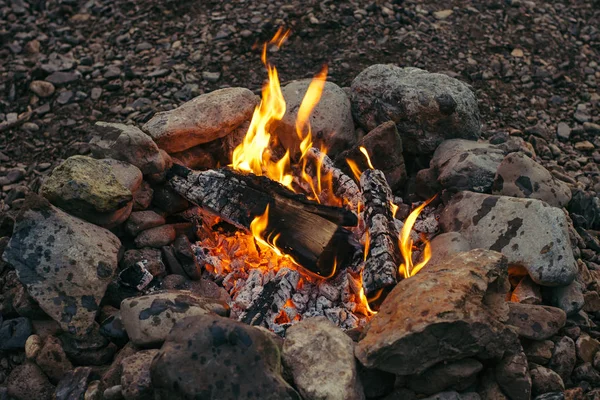 Evening small fire made of birch logs ennobled with stones. Warm hearth.