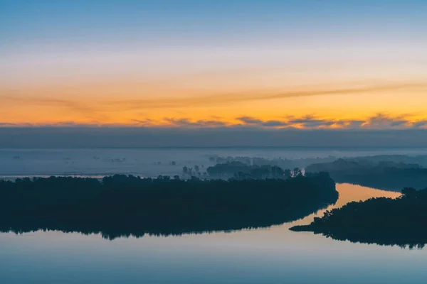 川の水に映る初期の青空 夜明け前の空の下に森と川岸 絵のように美しい空の黄色いストライプ 霧が島に木を隠した 雄大な自然の神秘的な朝の大気の風景 — ストック写真
