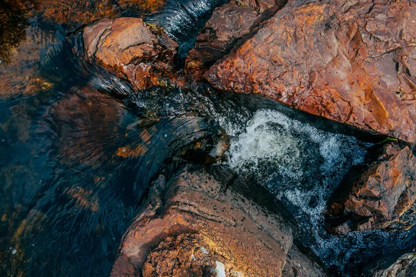 春水中光滑的石头特写 干净的水在红色和橙色的石头之间流动 五颜六色的自然背景山泉溪与复制空间 美丽的小溪纹理与湿石头 — 图库照片