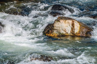 Dağ Deresi'ne yakın çekimde büyük kayalar. Kopya alanı ile hızlı nehir Rapids. Köpüklü su akıntısı. Isldeki taşların yanında hızlı akış. Temiz su dalgalarının arka planı. Dere parlak dere doğal doku