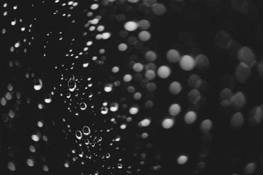 Yağmur damlalarıyla kirli pencere camı. Bokeh yağmur damlaları ile atmosferik tek renkli koyu arka plan. Damlacıklar ve lekeler kapanır. Makroda ayrıntılı saydam doku. Kopya alanı. Yağmurlu hava.