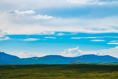 Karla dolu dev dağların muhteşem manzarası. Dağın üzerinde büyük bir bulut. Uçurumun üstündeki büyük kayalık kayalık. Harika vahşi manzara. Görkemli doğanın atmosferik yayla manzarası. Doğal dağ manzarası.