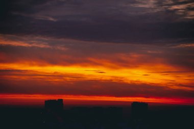 Harika varirenkli ateşli şafak ile Cityscape. İnanılmaz dramatik çok renkli bulutlu gökyüzü. Şehir binası çatılarının karanlık siluetleri. Bulutlu havalarda gün doğumunun atmosferik arka planı. Kopyalama alanı.
