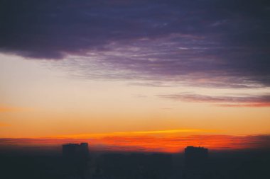 Harika varirenkli ateşli şafak ile Cityscape. İnanılmaz dramatik çok renkli bulutlu gökyüzü. Şehir binası çatılarının karanlık siluetleri. Bulutlu havalarda gün doğumunun atmosferik arka planı. Kopyalama alanı.