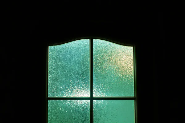 Dark silhouette of glass door in supernatural green light. Locked alone in room behind door on Halloween. Nightmare with aliens, monsters and ghosts. Evil in home. Inside haunted house. Alone in dark.